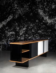 a black and white cabinet sitting in front of a wall with trees on it's side