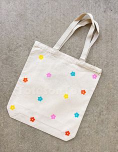 a white bag with multicolored flowers on it sitting on top of a floor