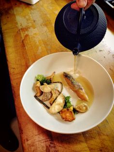 a person pouring sauce on a plate with food