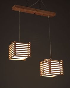 two wooden lights hanging from the ceiling in a dark room with no one around them