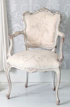 an old chair sitting in front of a wallpapered room