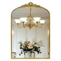 a vase with flowers is sitting in front of a mirror that has gold trim around it