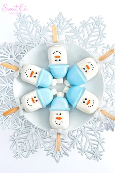 four marshmallows with snowmen on them in the middle of a plate