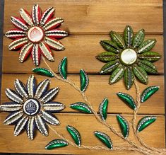 three decorative flowers are sitting on a wooden surface, one is green and the other is red