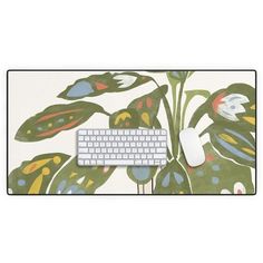 a computer keyboard sitting on top of a mouse pad with a plant design on it