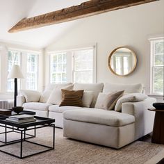 a living room with couches, tables and two large windows in it's center