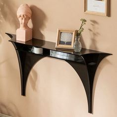 a black shelf sitting on top of a wall next to a vase