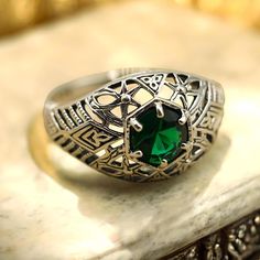 This elegant ring is a vintage piece crafted 925 solid sterling silver. It features a simulated emerald solitaire set in a beautiful filigree design. The ring is hallmarked with the stamp "925," indicating its authenticity and quality. Heirloom Style Green Filigree Jewelry, Antique Green Filigree Rings, Luxury Vintage Green Filigree Ring, Vintage Green Filigree Jewelry, Vintage Emerald Filigree Jewelry, Filigree Design, Elegant Ring, Green Gemstones, Solitaire Ring