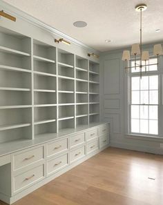 an empty room with white bookcases and wooden floors