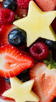 a bowl filled with fruit topped with star shaped cut out strawberries and blueberries