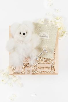 a white teddy bear sitting on top of a wooden box filled with baby's breath