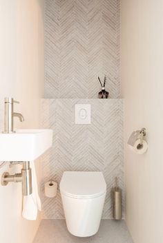 a white toilet sitting next to a bathroom sink under a faucet mounted on a wall