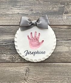 a personalized hand print on a paper plate with a gray bow around the edge