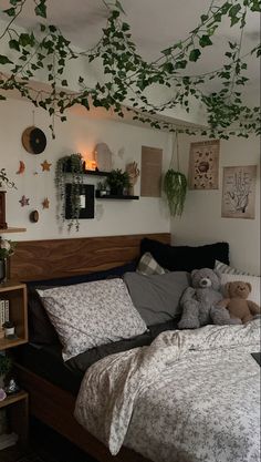 there is a bed with two teddy bears on it and plants hanging from the ceiling