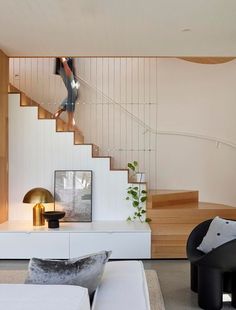 a living room with white furniture and wooden stairs