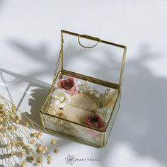 an open box with flowers inside sitting on a table next to some dried flowers and a plant