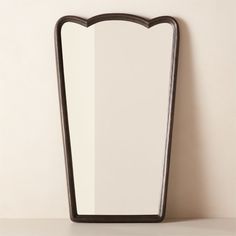 an empty mirror on the wall next to a shelf with a vase in front of it