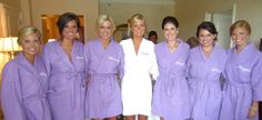 four women in purple robes are posing for a photo with one woman wearing a white robe