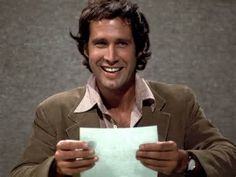 a smiling man holding up a piece of paper