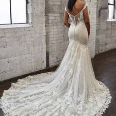 a woman in a white wedding dress is looking down at the back of her gown