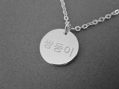 This is a personalized engraved Korean name round pendant sterling silver necklace. The sample necklace is made with the word a twin in Korean in the font style #1. Please check the font options in the pictures. One side or both sides, front & back can be engraved in Korean and numbers. The sample pendant is 15 mm wide. The available 2 pendant sizes are 15 mm and 20 mm. All orders come gift-wrapped. << How to order >> Please choose the engraving side, pendant size and necklace length from the options. Leave the name and font style number you want. The thinner chain is the same chain used in the dainty mini necklace. We'll translate the name for you if you don't know the language. If you don't choose a font, the font used for the sample will be used. The font #2 will be used for numbers if Korean Necklace, Roman Letters, Korean Characters, Necklace Korean, Word A, Mini Necklace, Korean Jewelry, Round Pendant Necklace, Korean Name