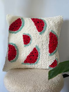 a crocheted pillow sitting on top of a chair next to a potted plant