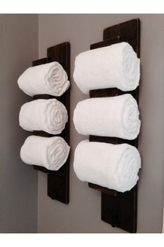 four white towels are hanging on the wall next to a brown towel rack with three folded ones