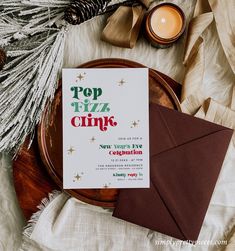 a table topped with an envelope next to a candle and some christmas decorations on top of it