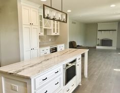 an empty kitchen with white cabinets and marble counter tops