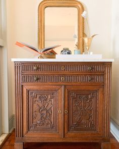 an ornate wooden cabinet with a mirror and vases on the top shelf next to it