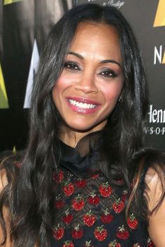 a woman with long black hair wearing a red and black dress smiling at the camera