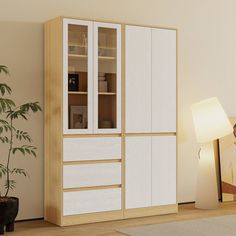 a living room with a white and wood cabinet next to a potted plant on the floor