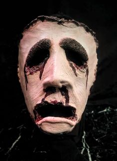 a creepy mask with blood all over it's face and nose, on a black background