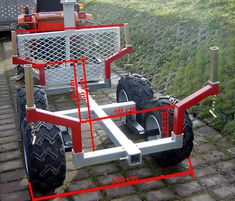 a red and white cart sitting on top of a brick road next to a field