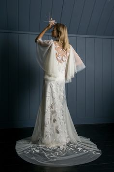 a woman in a white wedding dress standing on a black floor with her back to the camera