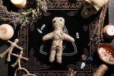 a voodoo doll surrounded by candles, wicks and other items on a black mat