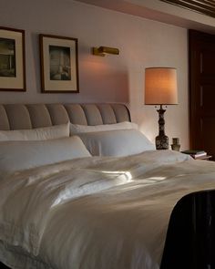 a bed with white sheets and pillows in a bedroom