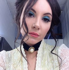 a close up of a woman wearing a choker and eyeliner with blue eyes