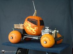 a car made out of pumpkins sitting on top of a blue table next to a black wall