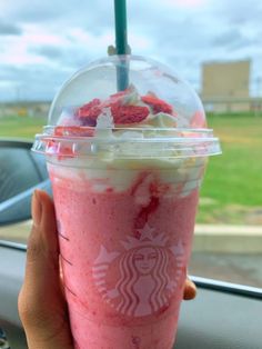 someone holding up a pink drink with strawberries in it