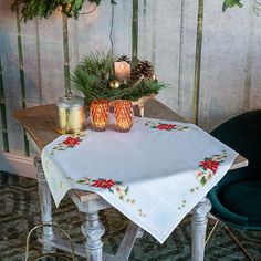 a table with two candles on it and a christmas tree in the corner next to it