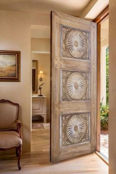 an open door leading to a living room with a chair and painting on the wall