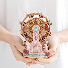 a person holding a miniature ferris wheel in their hands