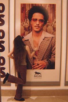 a woman standing next to a poster with a man's face on the wall