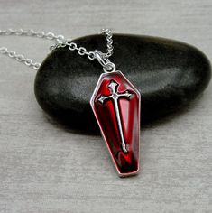 "This Coffin charm necklace comes on a silver-plated chain that is available in different lengths. Please choose your desired length from the drop-down menu when placing the item in your shopping cart.  { CHARM DETAILS } ★ Material: Silver Plated and Enamel  ★ Finish Color: Silver & Red ★ Measurements: 1/2\" x 1\" ★ Dimensions: One-sided { SIMILAR ITEMS }  More Halloween themed items available from my shop: https://www.etsy.com/shop/treasuredcharms/search?search_query=halloween { GIFT OPTIONS } Gift boxes are available at no additional cost and can be added from the drop-down menu during checkout.   You can mark it as a gift, add a gift message, and send it directly to a recipient by entering their address in the 'shipping address' during checkout.  Receipts with price information are not Gothic Cross Pendant Jewelry For Halloween, Cross-shaped Halloween Jewelry Gift, Halloween Gift Necklace With Cross Pendant, Halloween Gift Cross Pendant Necklace, Halloween Silver Jewelry With Cross Pendant, Silver Cross Pendant Jewelry For Halloween, Silver Cross Necklace For Halloween, Gothic Red Nickel-free Necklace, Red Gothic Necklace Nickel Free