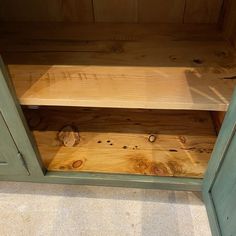 a wooden shelf with two doors open on the floor