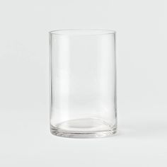 a clear glass is sitting on a white surface with no one around it and the bottom half empty