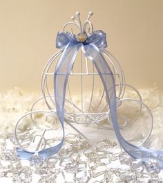 a small metal ball with blue ribbon and bow on top of white furnishing