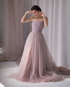 a woman in a pink dress is posing for the camera with her hand on her head