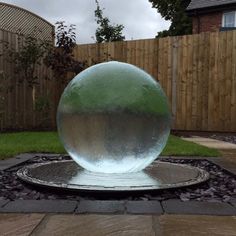 a large glass ball sitting on top of a stone slab in the middle of a yard